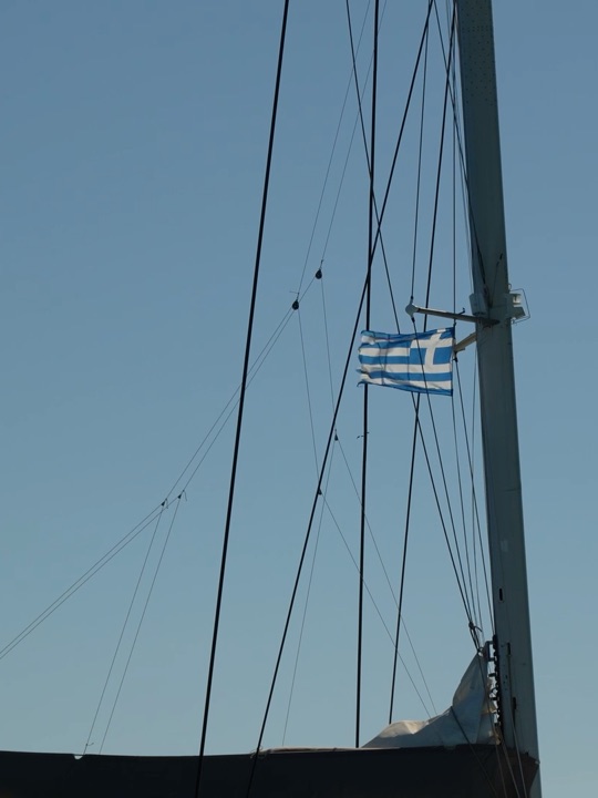 The mast and the Greek flag against a clear sky