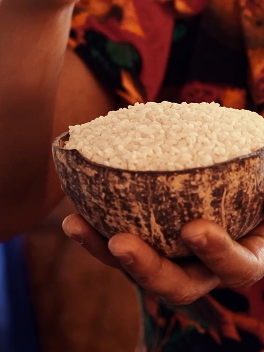 Hands holding a coconut shell of rice